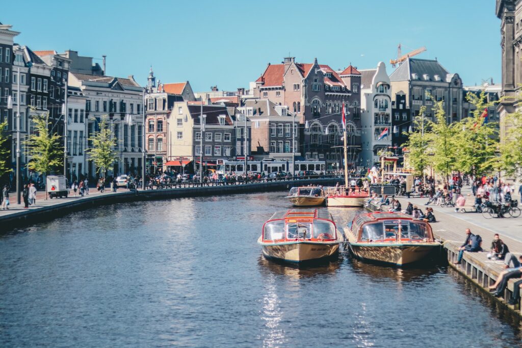 Canal boats and historic buildings in Amsterdam city centre during a sunny afternoon