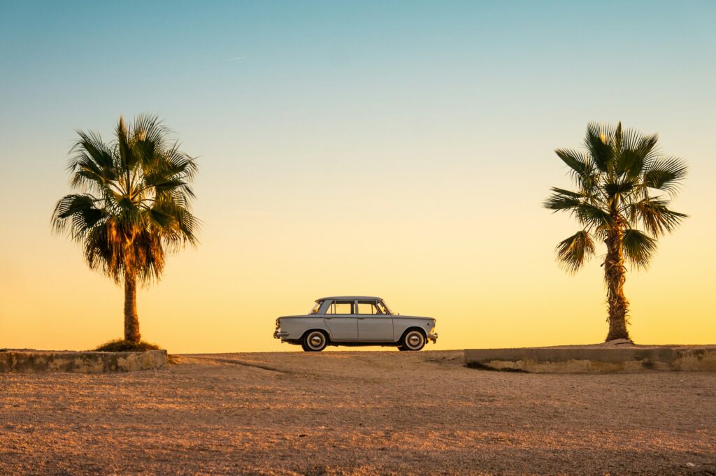 Best underrated summer destinations in Europe with vintage car and palm trees at sunset