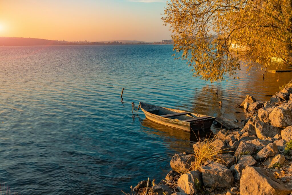 Small wooden boat beside a lake surrounded by golden autumn trees in Europe